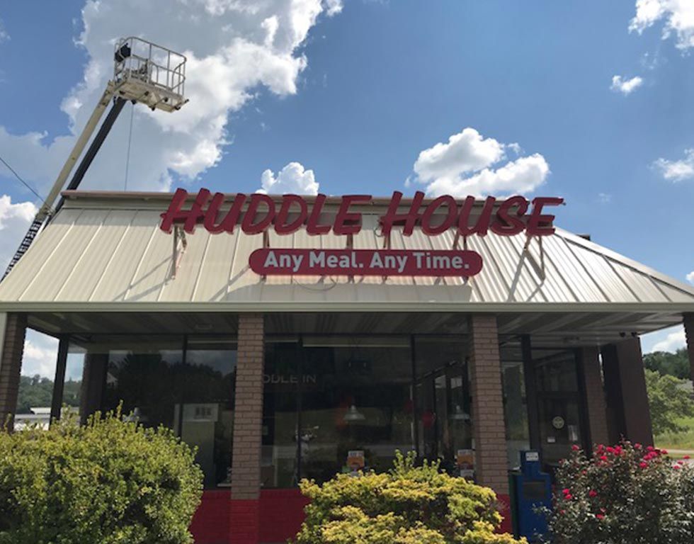 Huddle House restaurant sign with cherry red letters, advertising 