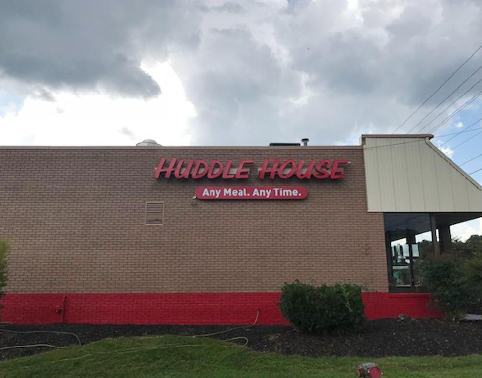 Huddle House restaurant sign on a brick building, red letters on the sign, with the slogan 