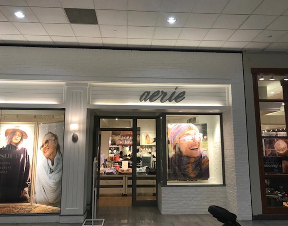 Aerie store front at a mall with large window displays featuring smiling women and clothing.