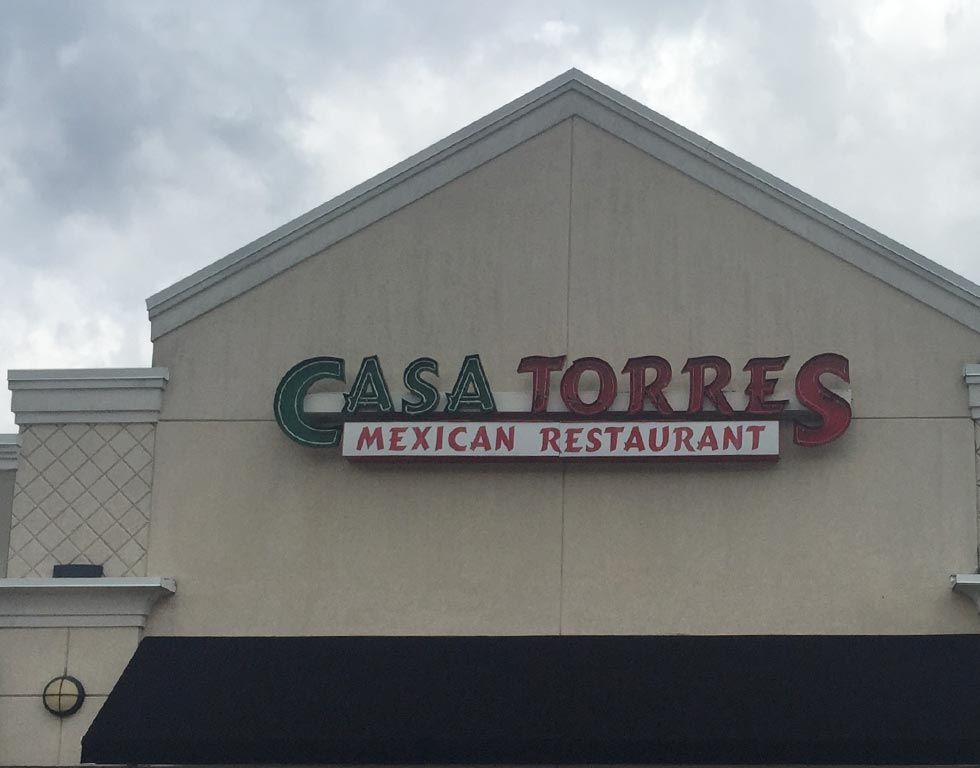 Casa Torres Mexican Restaurant sign in green and red against a beige building under a cloudy sky.