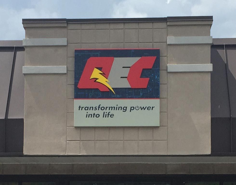 Sign for AEC, an electrical company. The logo features the letters AEC in red and a yellow lightning bolt. The tagline reads, 
