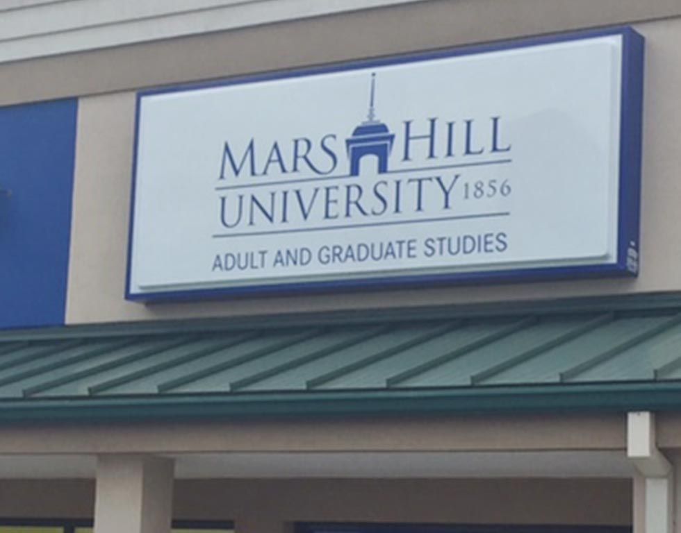 Sign for Mars Hill University, white with blue trim. Includes the university logo, text 