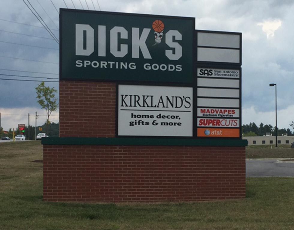 Sign for a shopping center with Dick's Sporting Goods and Kirkland's. Other storefronts include Mad Vapes and Supercuts.