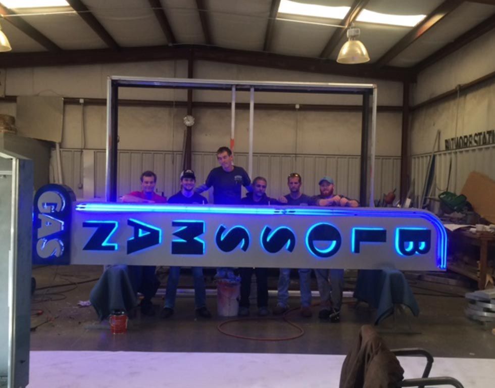 A group of six people standing behind a lit-up 