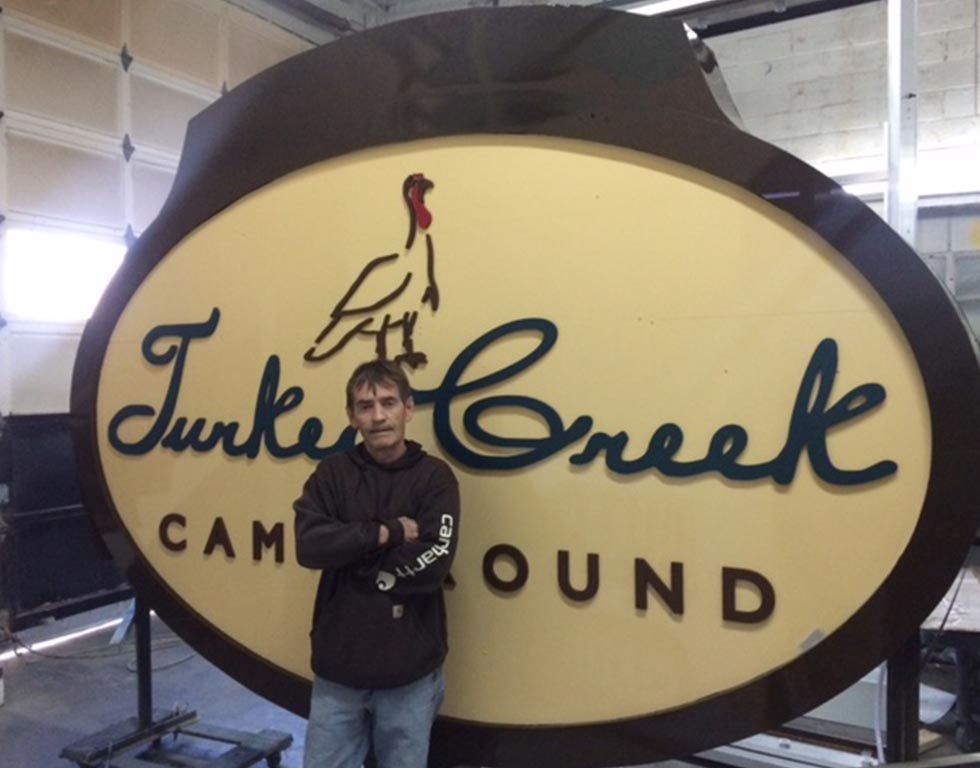 A man stands next to a large, custom sign for 
