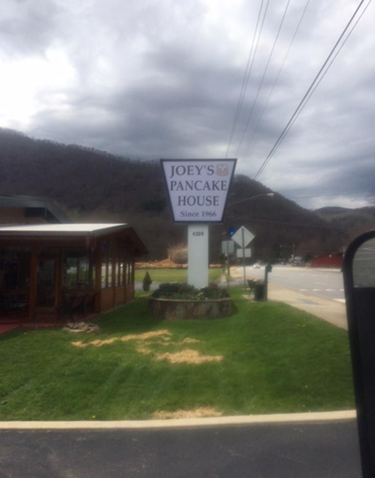 Joey's Pancake House sign in front of a mountain backdrop, with a covered outdoor seating area visible to the left.