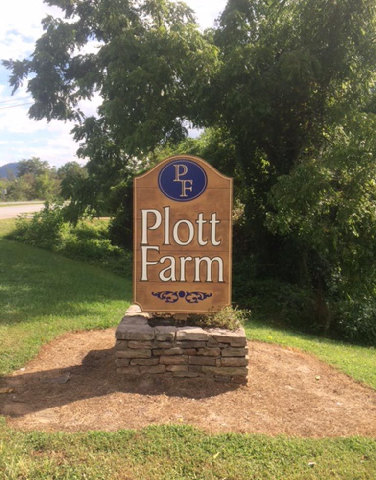 Sign for Plott Farm; brown wooden sign with 