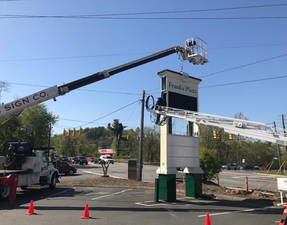 A sign company truck uses a boom lift to work on a sign for 