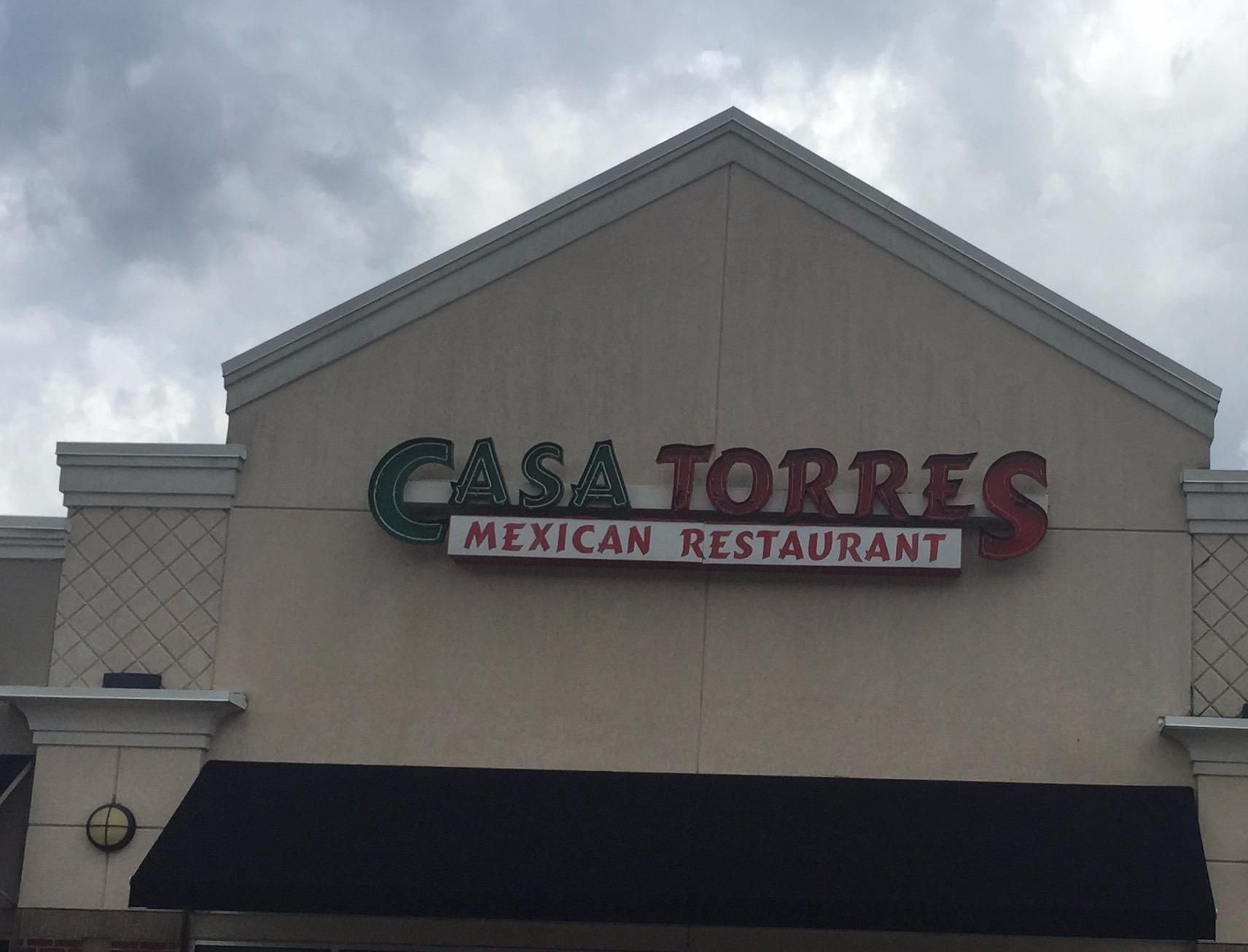 Casa Torres Mexican Restaurant sign on a beige building with red and green lettering under a cloudy sky.