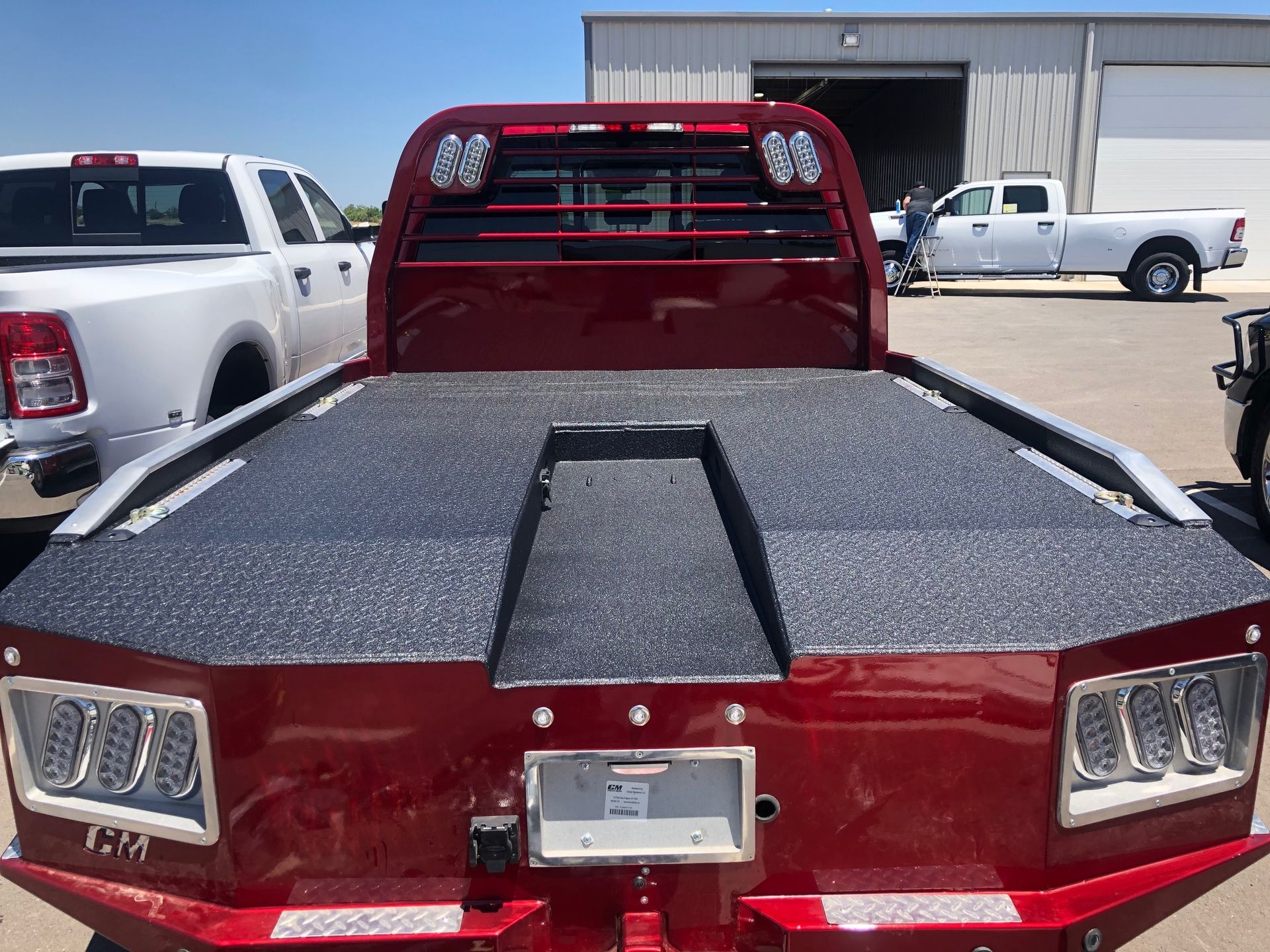 A red truck is parked in a parking lot next to a white truck.