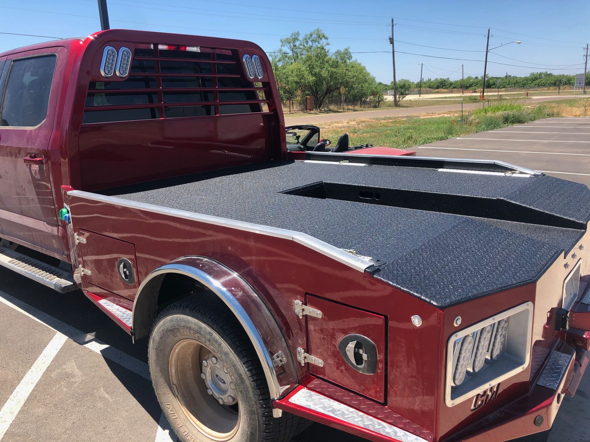 A red truck with a trailer attached to it is parked in a parking lot.