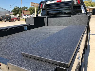 A truck is parked in a parking lot with the bed open.