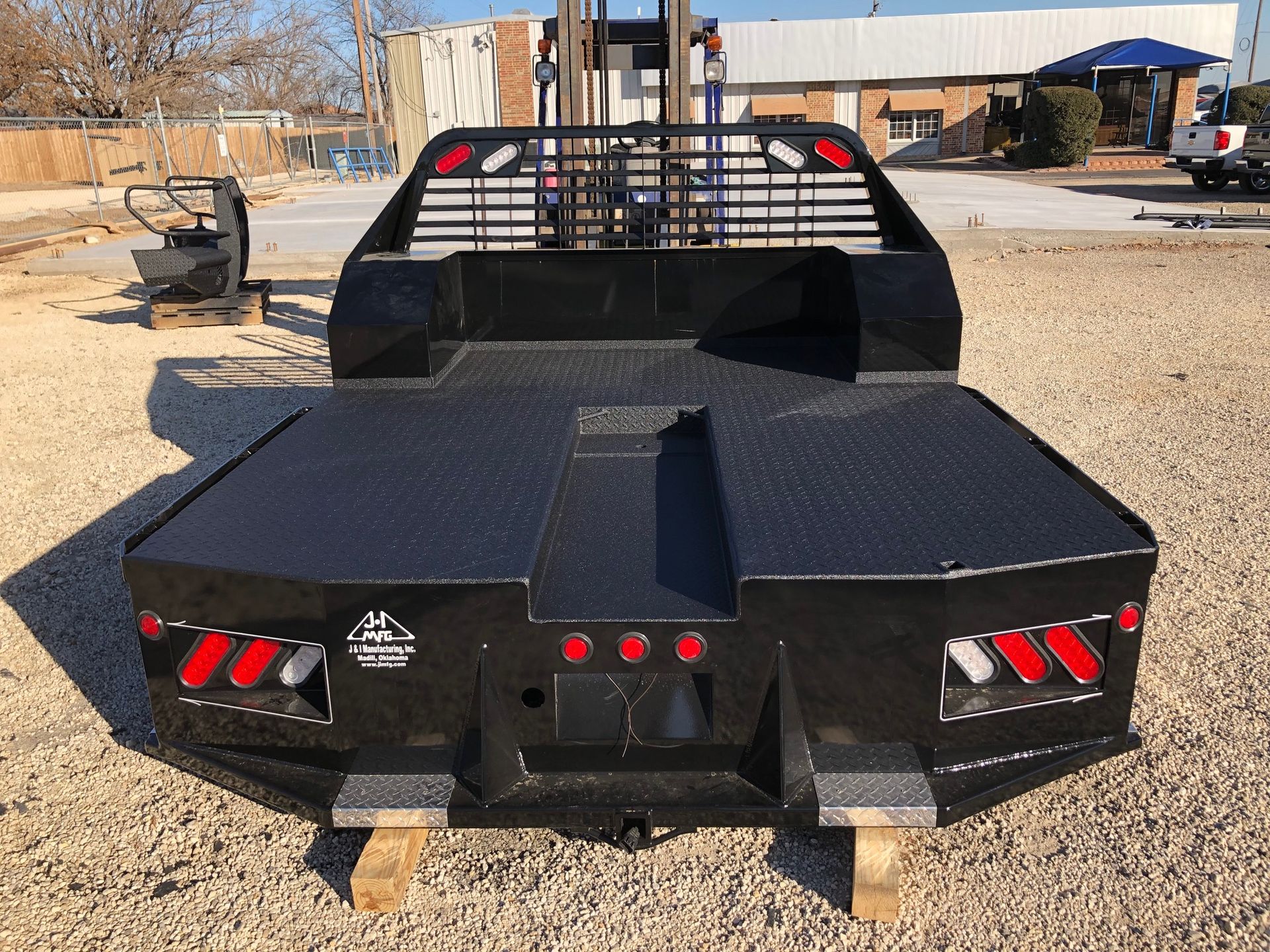 A black truck bed is sitting on top of a gravel road.