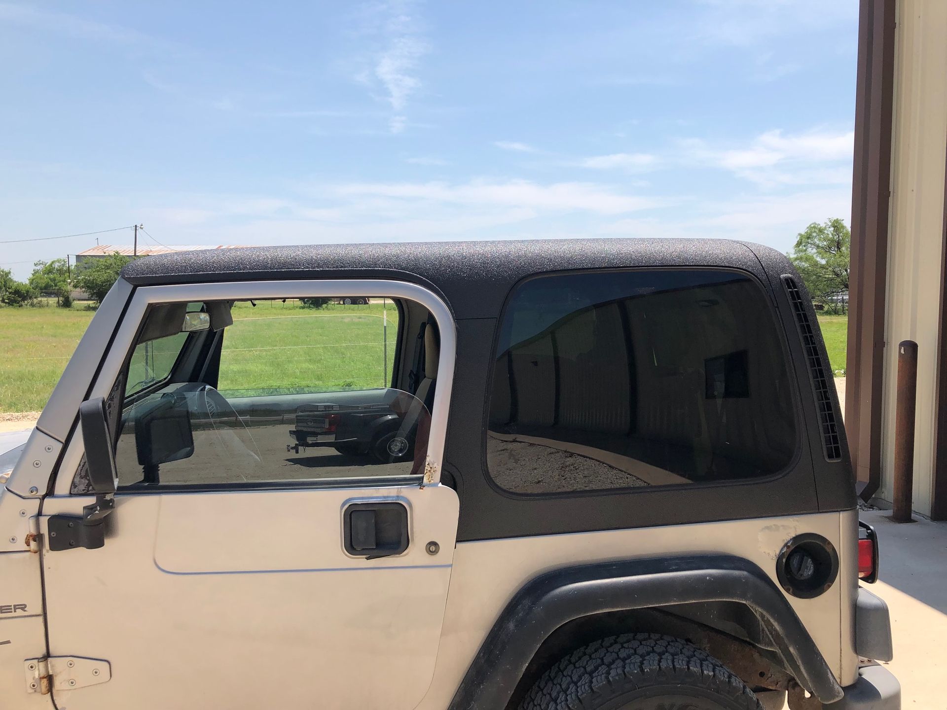 A white jeep with a black top is parked in front of a building.
