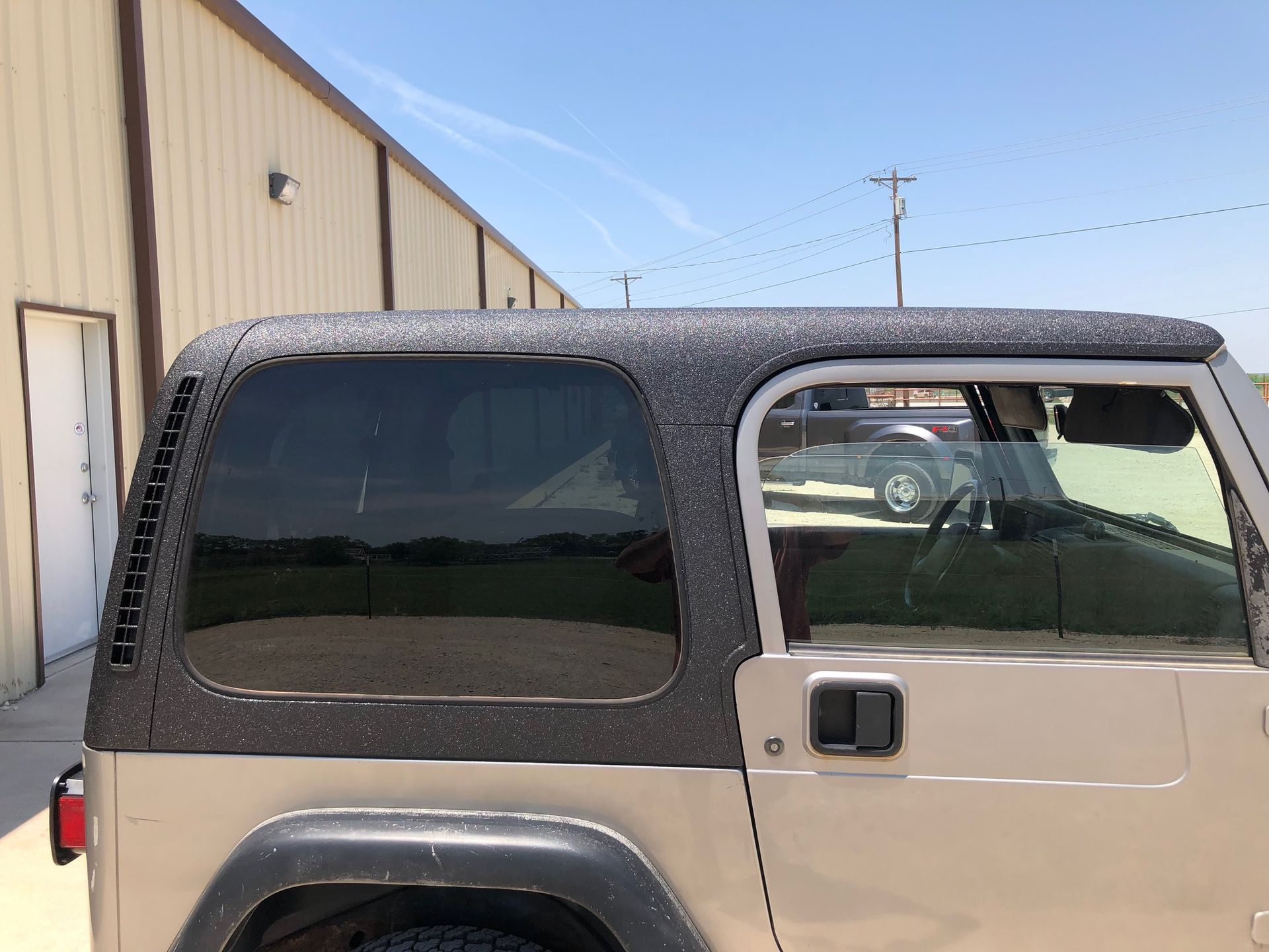 A jeep with a hard top is parked in front of a building.