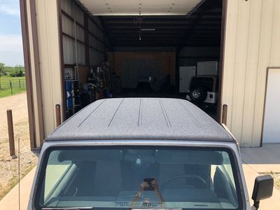 A jeep is parked in a garage with the roof up