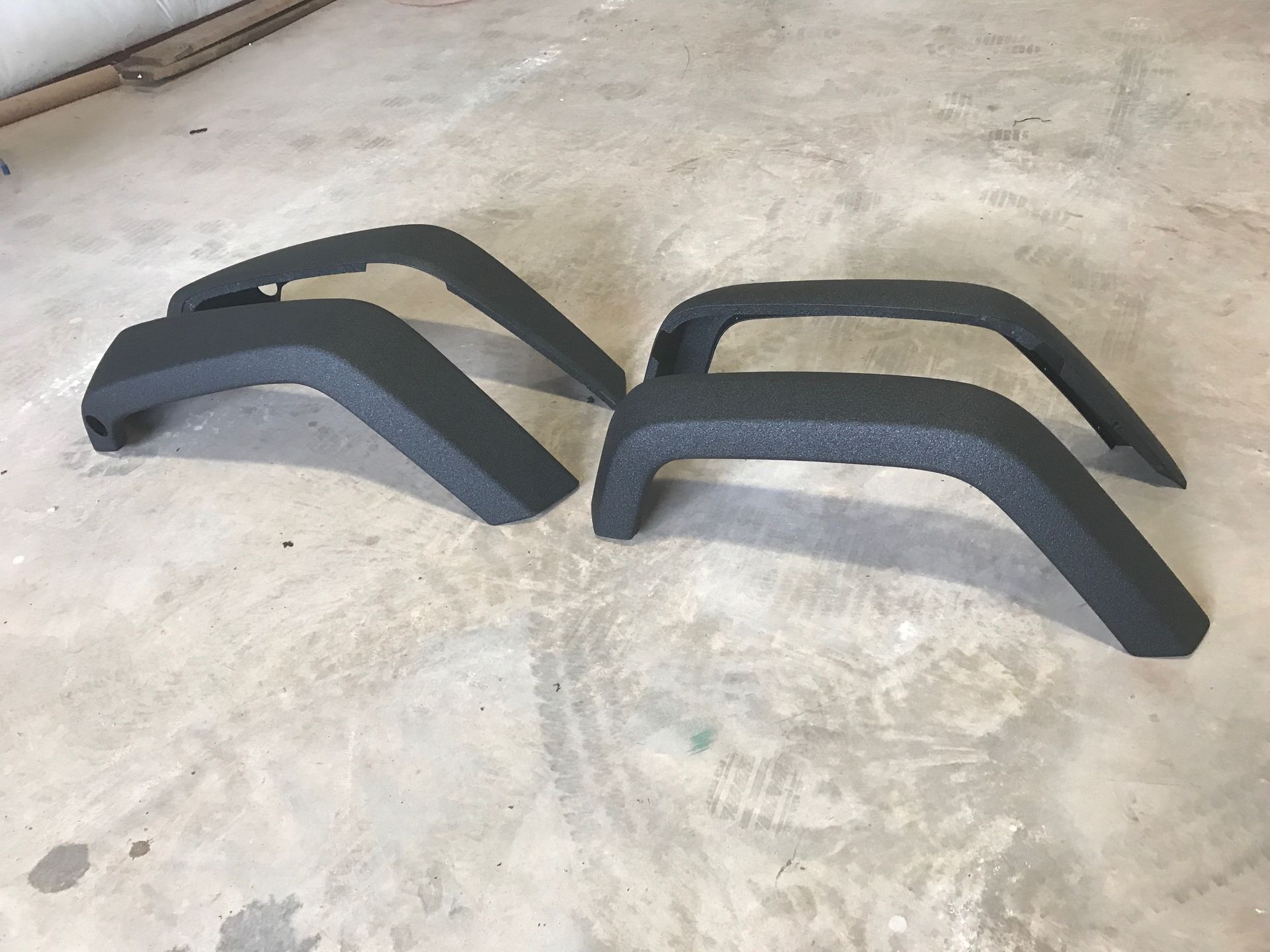 A pair of black fender flares are sitting on a concrete floor.