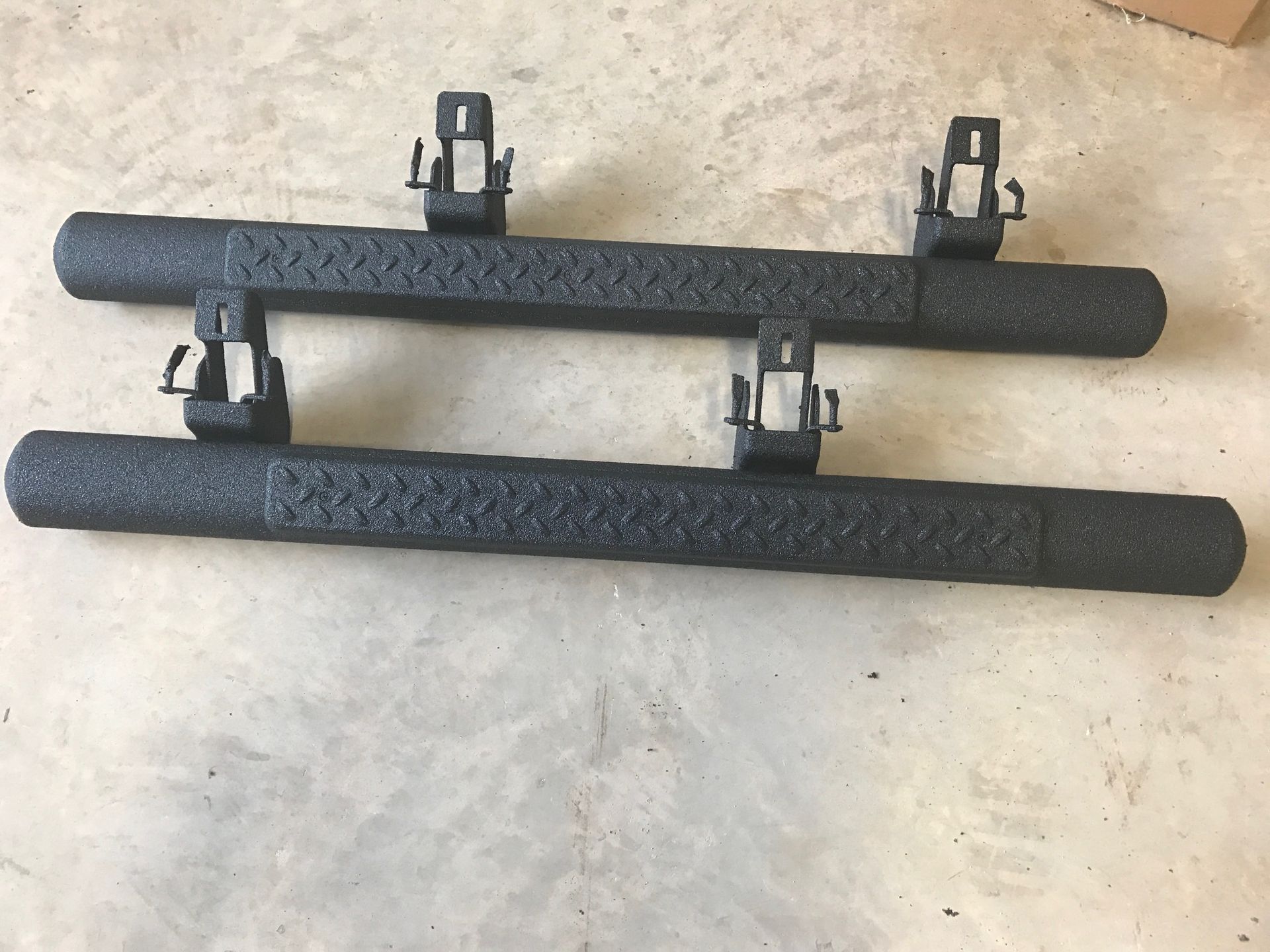 A pair of black side steps are sitting on the ground