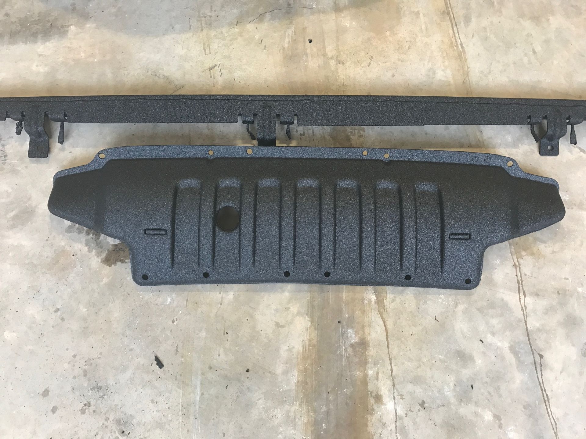 A black piece of metal is sitting on a concrete surface.