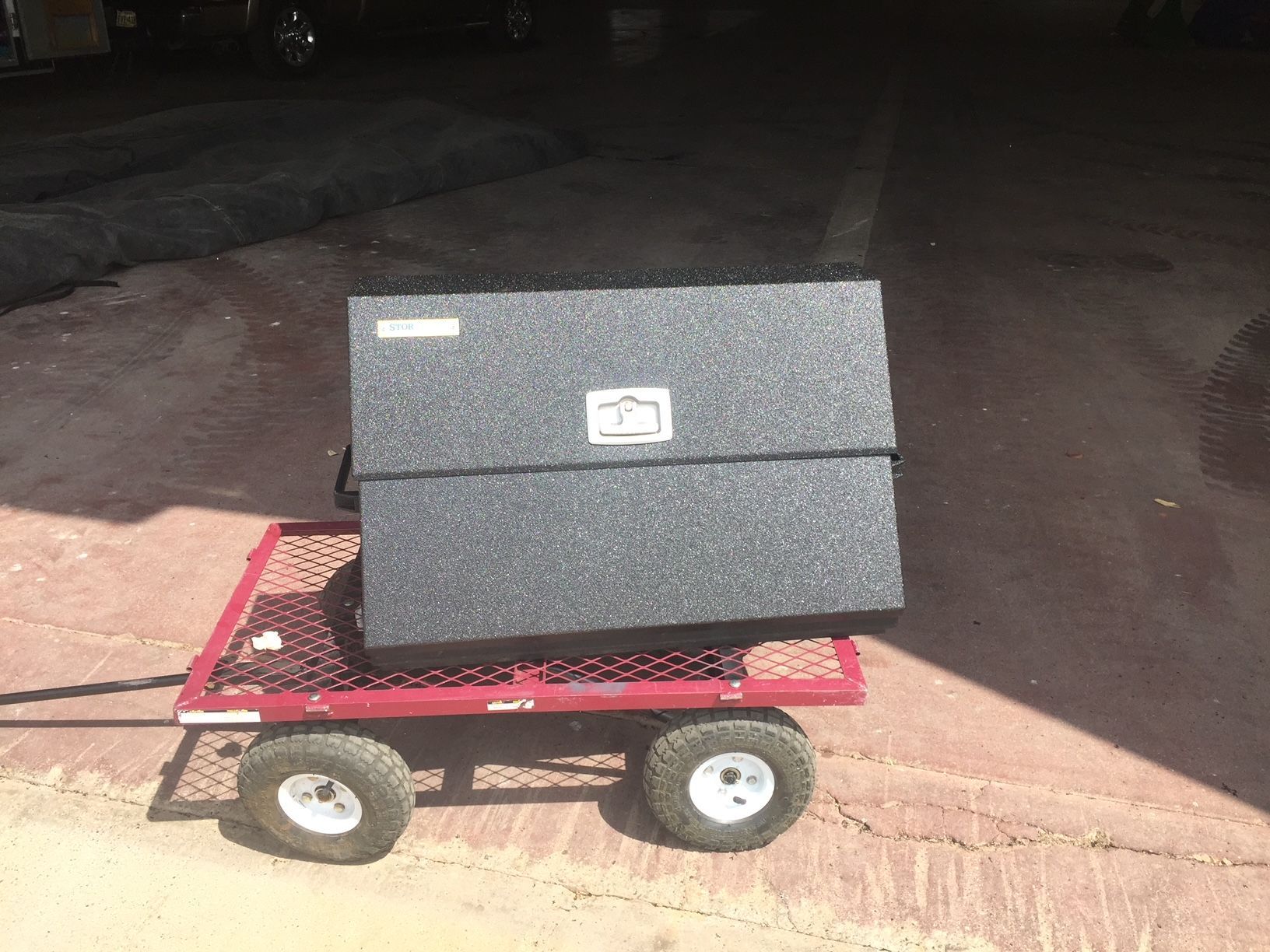 A black box is sitting on top of a red wagon.