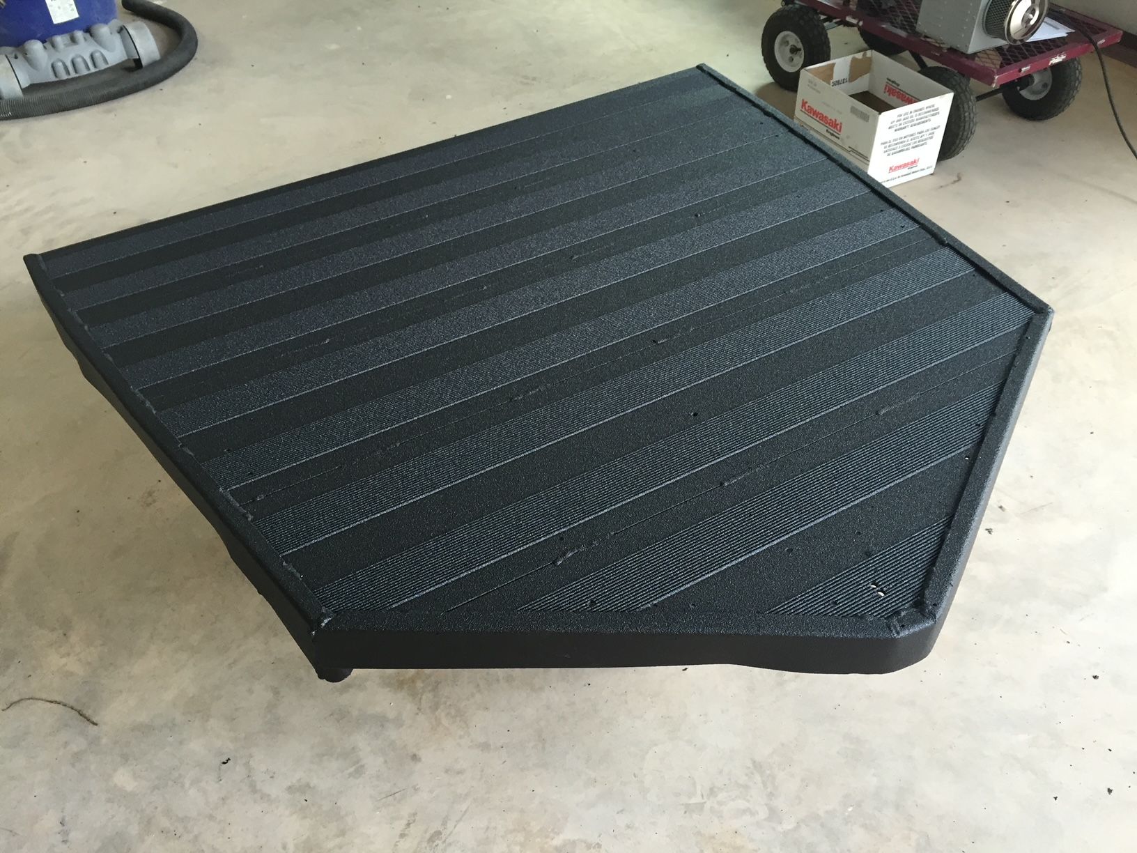 A black mat is sitting on a concrete floor in a garage