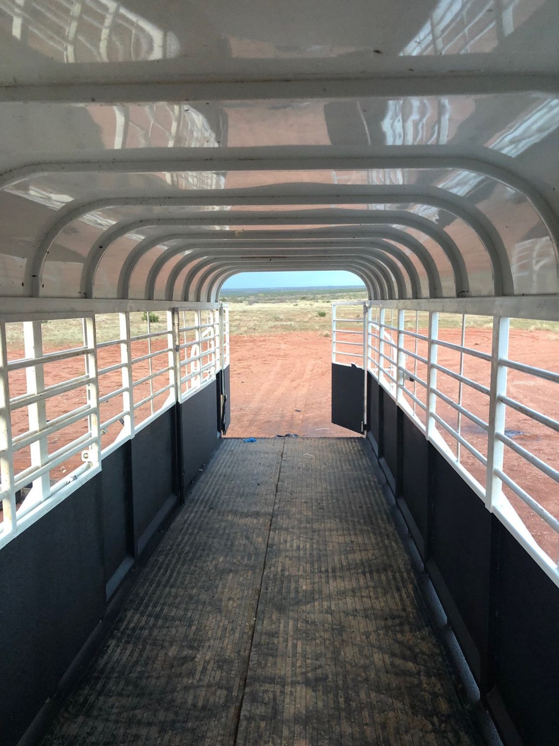 The inside of a horse trailer with a fence and a door