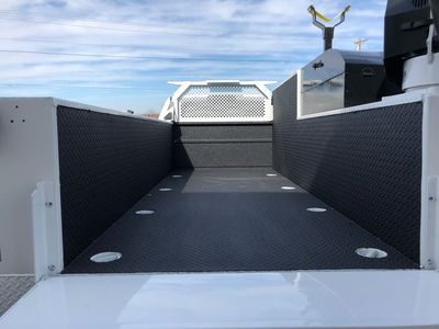 The back of a truck with a white bed and a black floor.