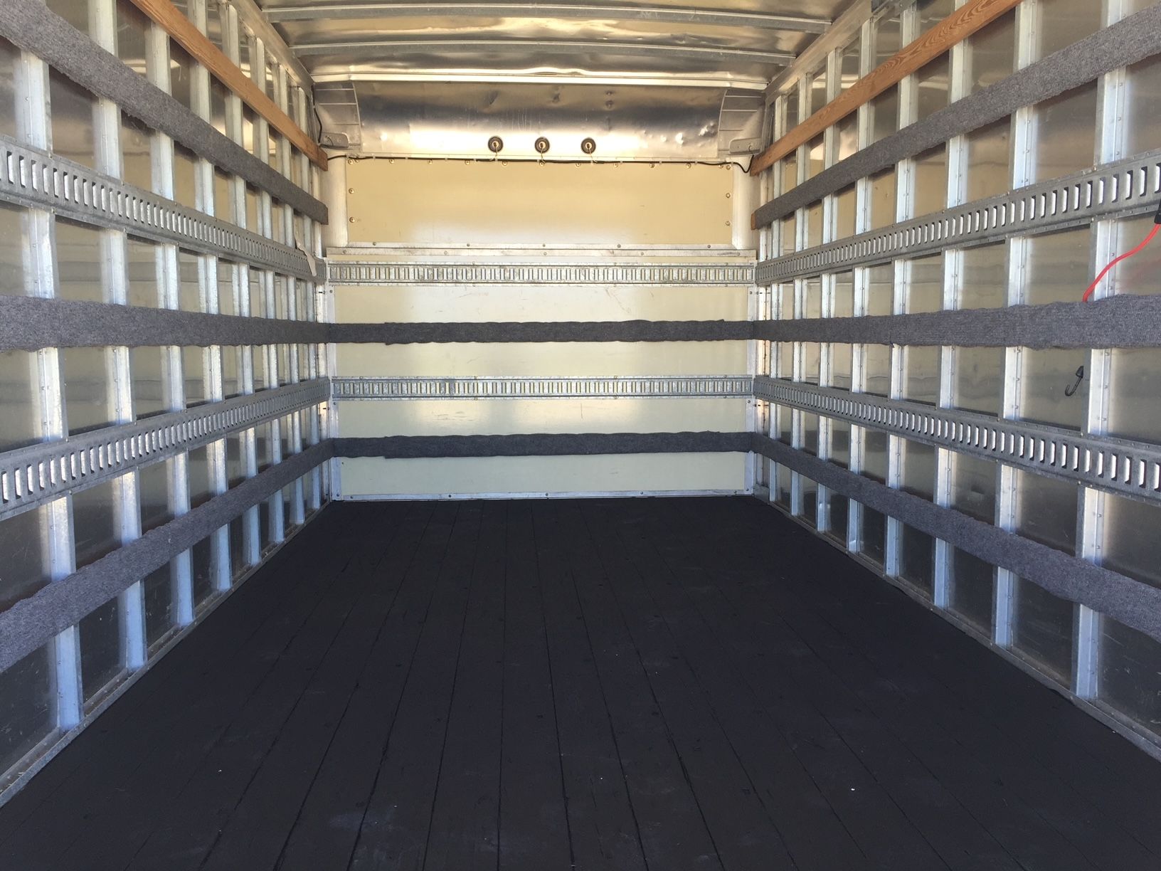 The inside of a truck with lots of shelves and a black floor.