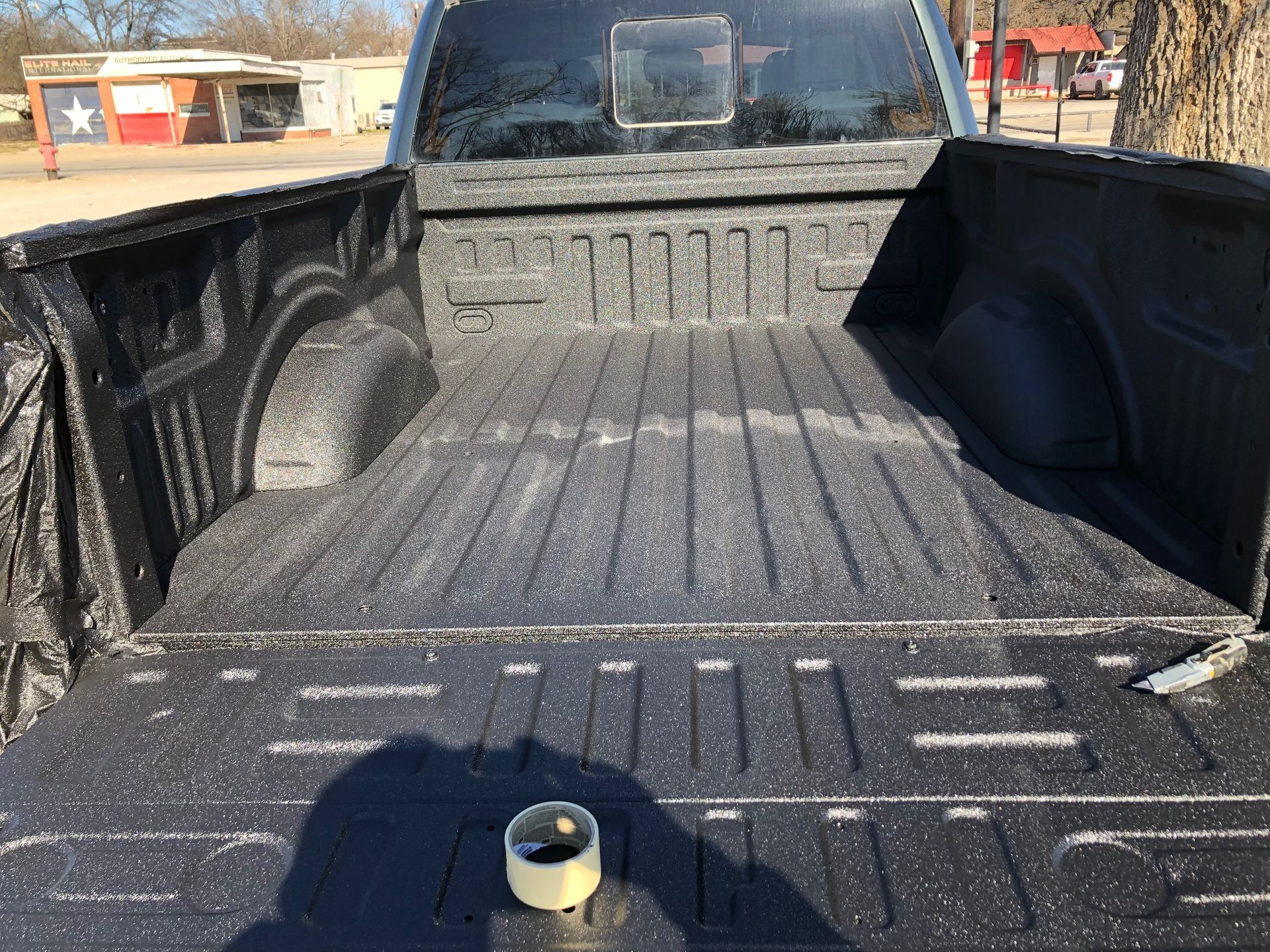 The back of a truck with a roll of tape in the bed.