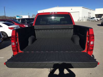 A red truck with a black bed is parked in a parking lot.