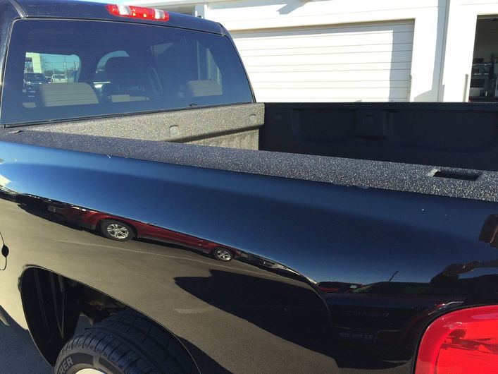 A black truck is parked in front of a garage door