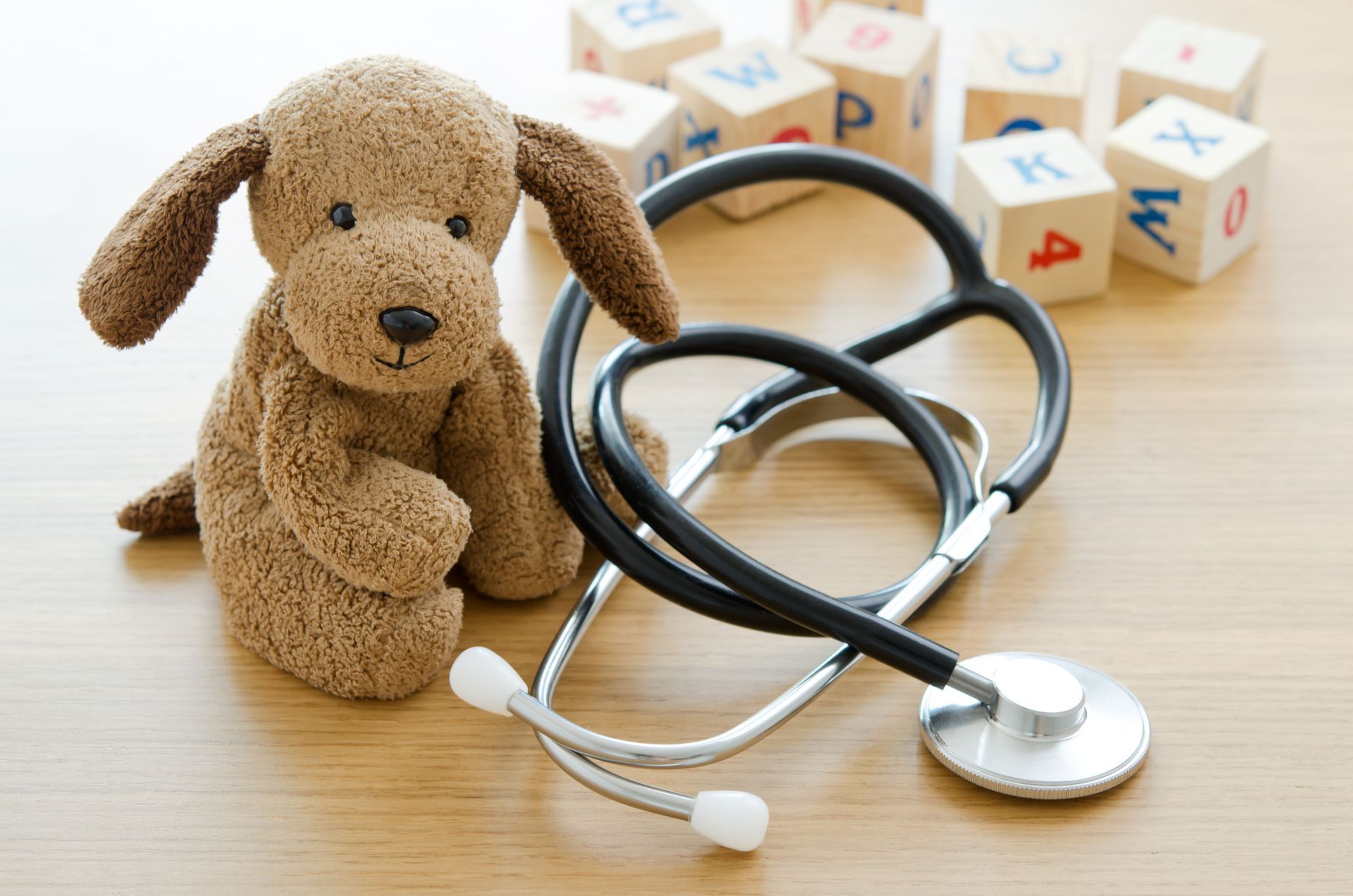 A stuffed dog is sitting next to a stethoscope on a table.