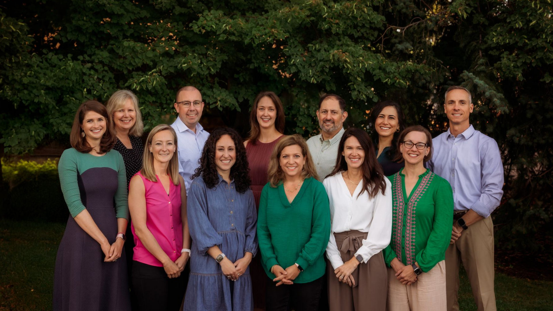 A group of people are posing for a picture in front of trees.