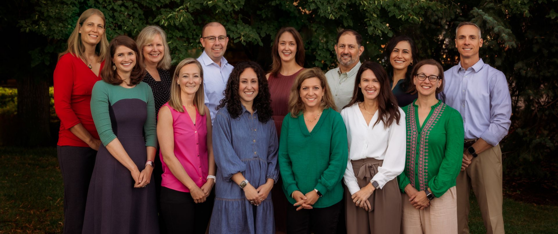 A group of people are posing for a picture in front of trees.