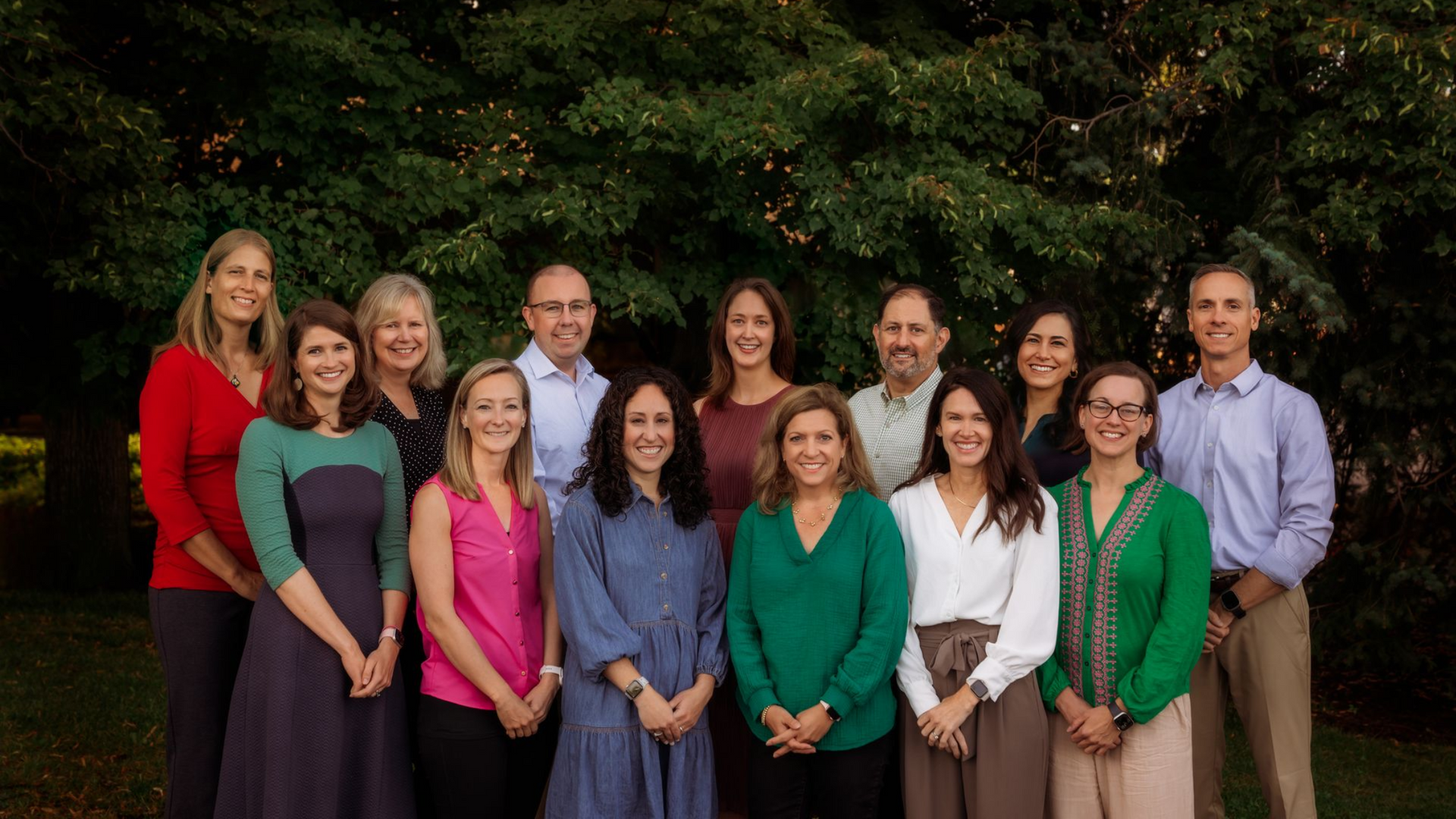 A group of people are posing for a picture in front of trees.