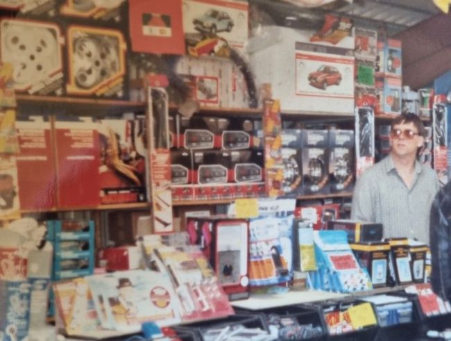 A man is standing in front of a store full of toys