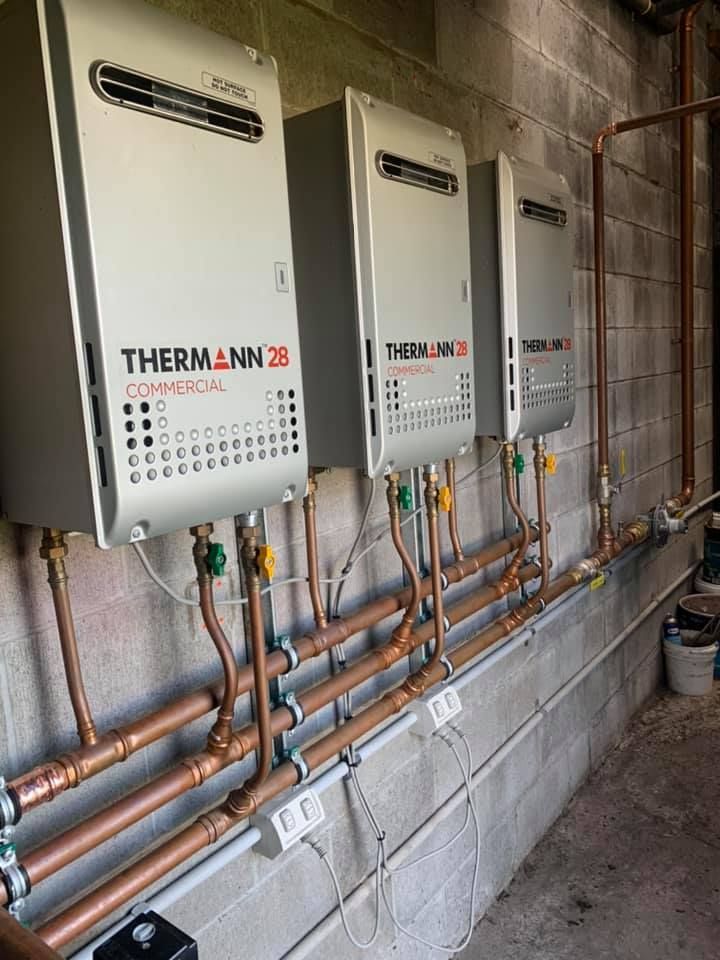 Three wall-mounted THERMA-LUX control units above copper piping in an unfinished utility room Three wall-mounted THERMA-LUX control units above copper piping in an unfinished utility room