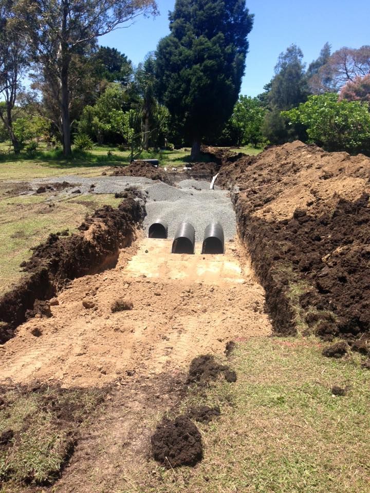 Concrete drainage culvert installed in a dirt trench at a grassy construction site. Concrete drainage culvert installed in a dirt trench at a grassy construction site.