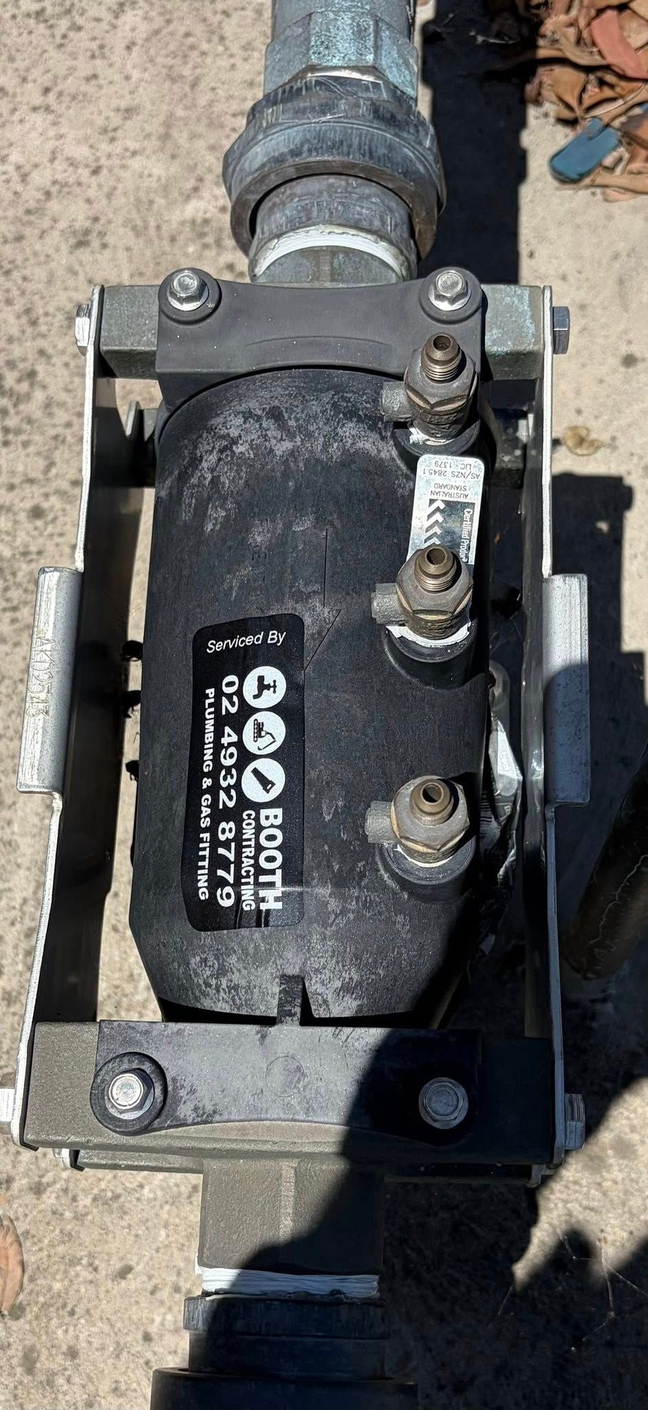 Black industrial pump or valve assembly with bolts and pipes on a concrete surface Black industrial pump or valve assembly with bolts and pipes on a concrete surface