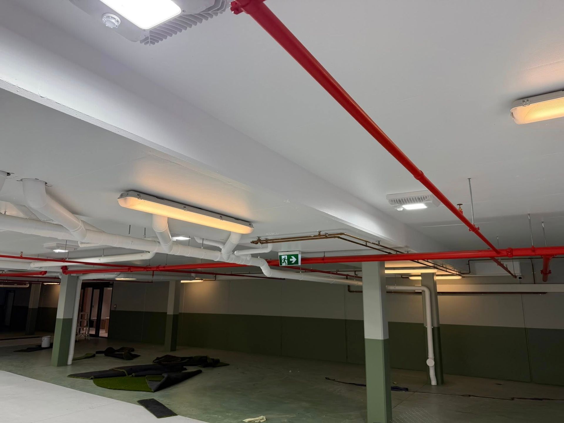 Parking garage ceiling with red pipes, fluorescent lights, and green-and-white walls Parking garage ceiling with red pipes, fluorescent lights, and green-and-white walls