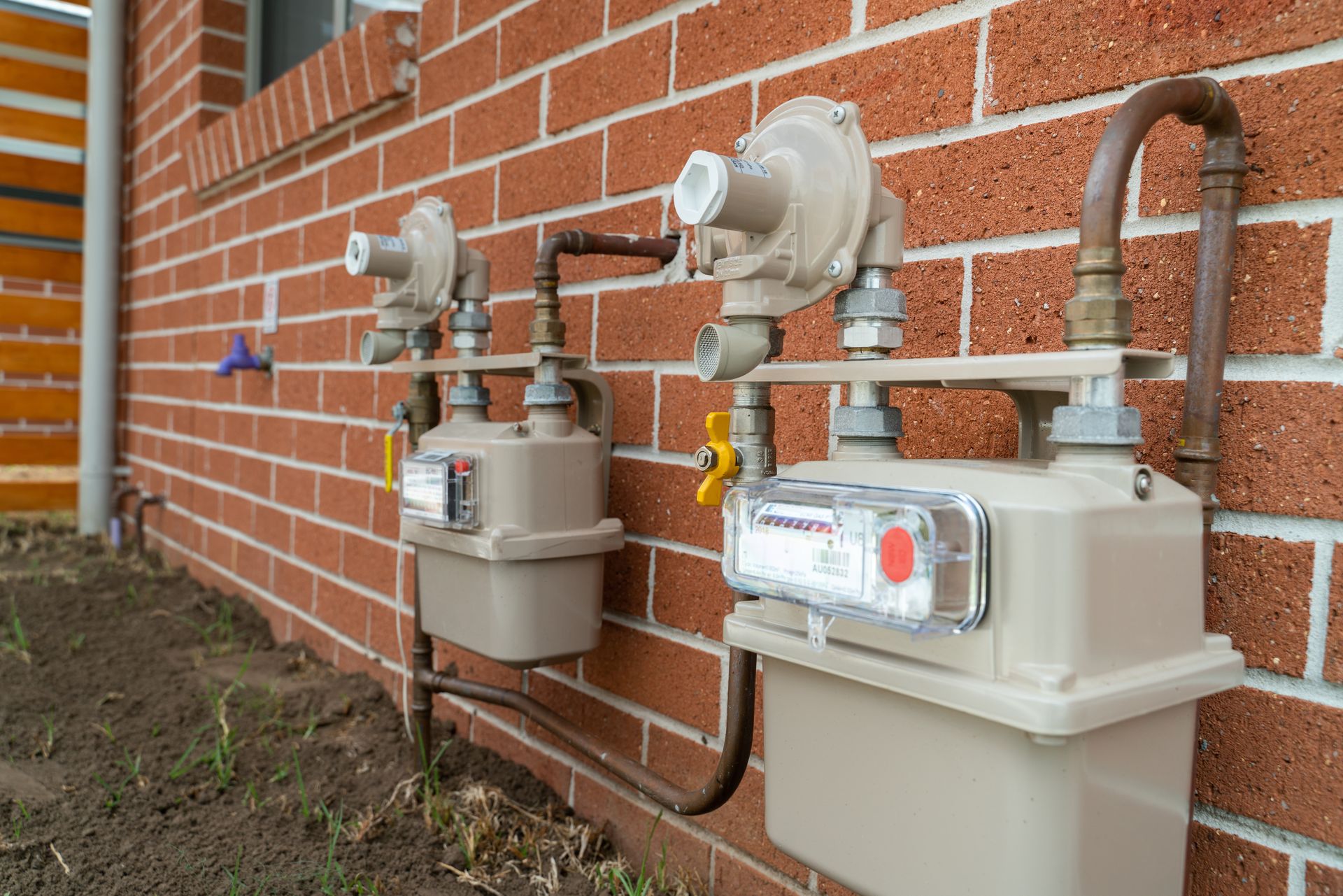 Gas meters and utility equipment mounted on a brick house exterior Gas meters and utility equipment mounted on a brick house exterior