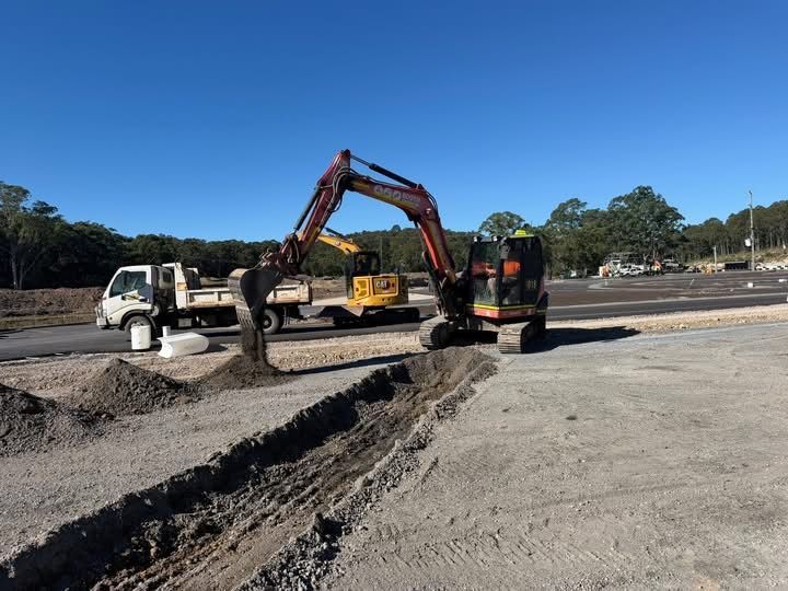 Excavator and dump truck working on a road construction site under a clear blue sky