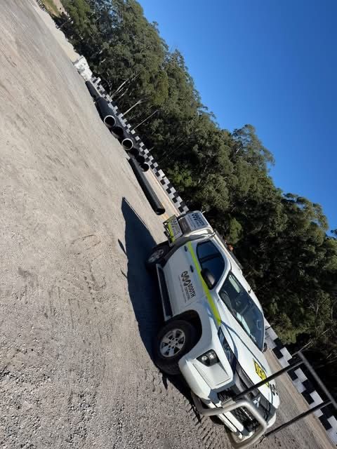 White pickup truck parked on a paved lot beside stacked tires under a clear blue sky