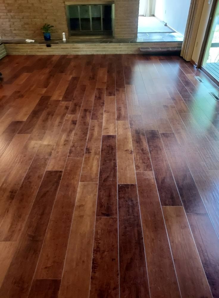 Hardwood flooring with varied brown tones installed in a room leading to a brick fireplace.