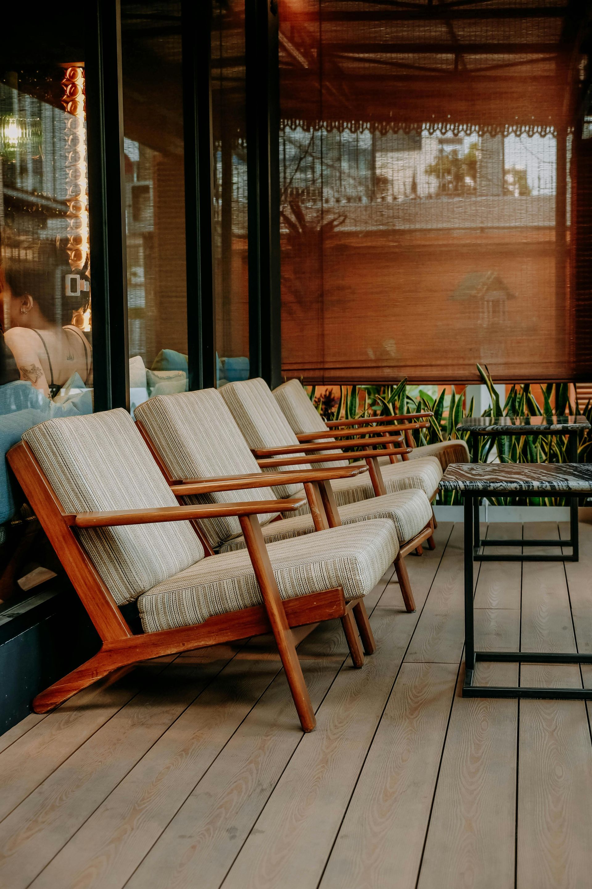 A screened-in porch with white wooden railings and a wooden floor, opening to a yard with a parked white van.
