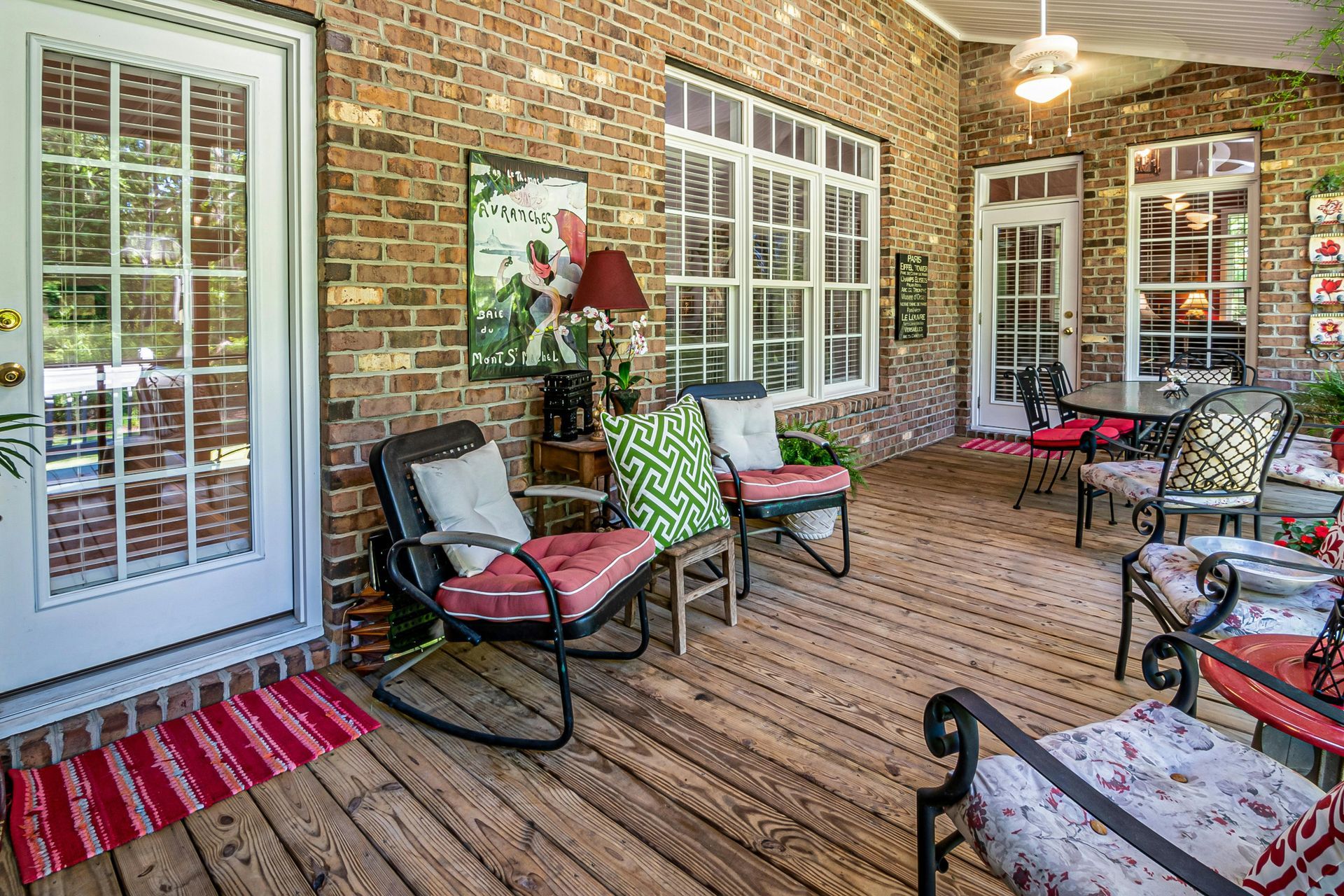 A partially open white sliding glass door with a grid pattern, installed on a house with beige siding and a wooden deck.