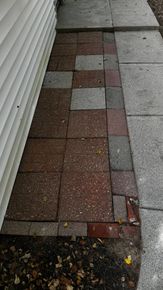 A sidewalk with bricks and granite next to a house.