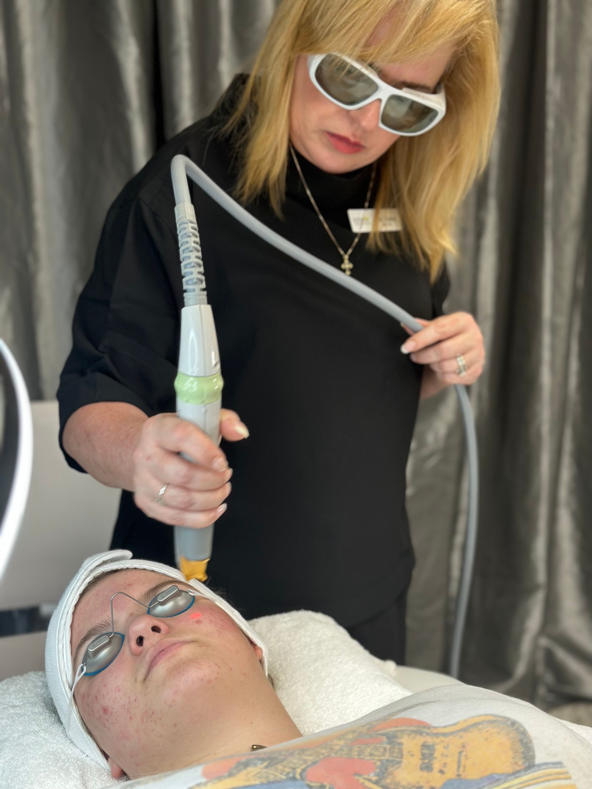 A woman is using a laser on a man 's face.