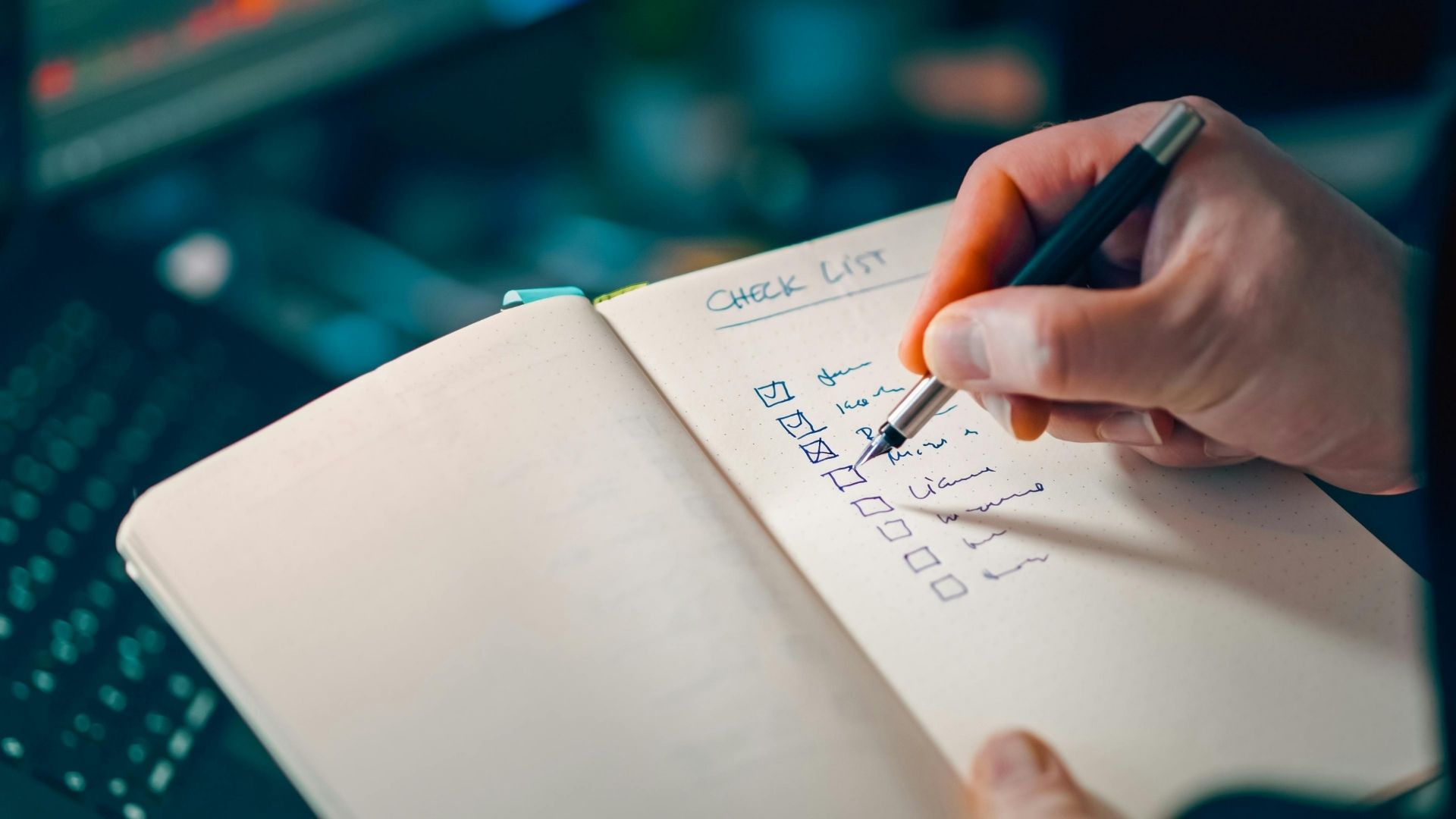 Hand writing a checklist in a notebook with a pen on a desk