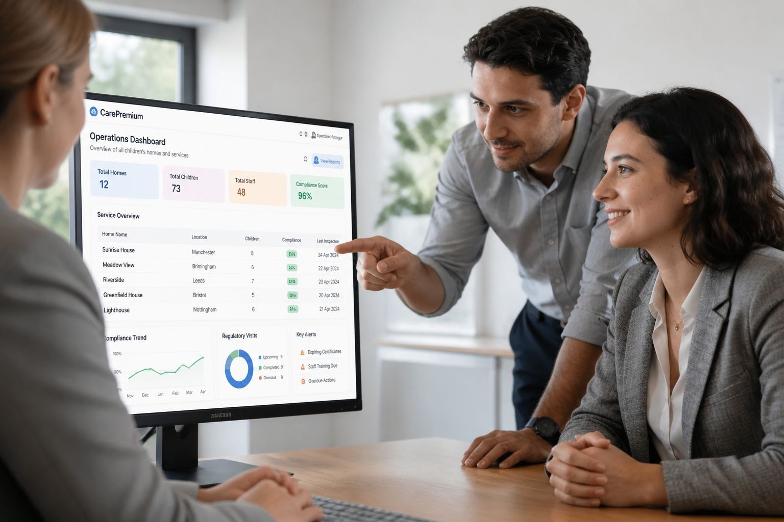Two colleagues discussing a laptop dashboard in a bright office, one pointing at the screen while smiling.